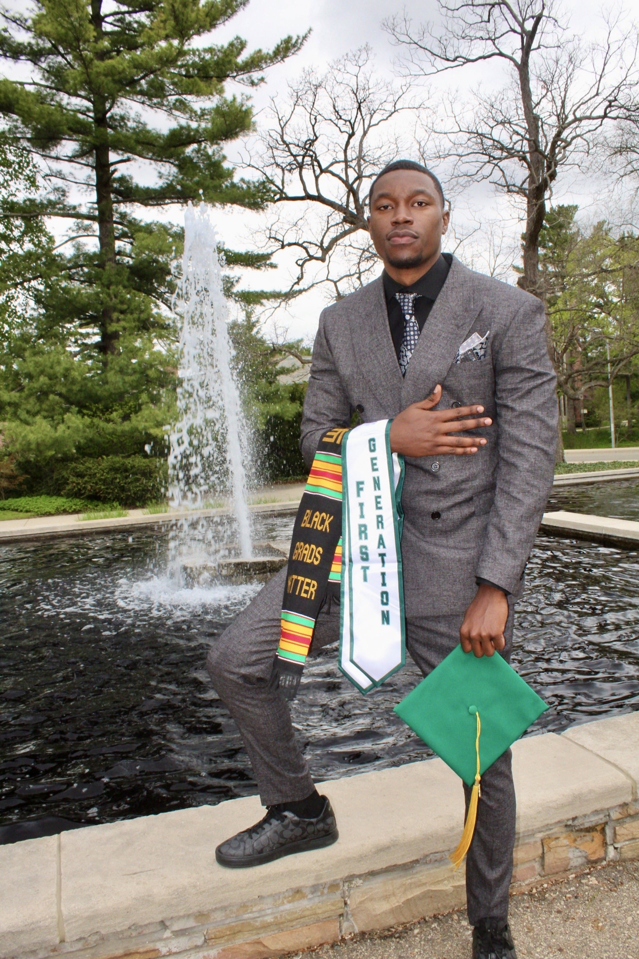First-generation graduate portrait beside a campus fountain